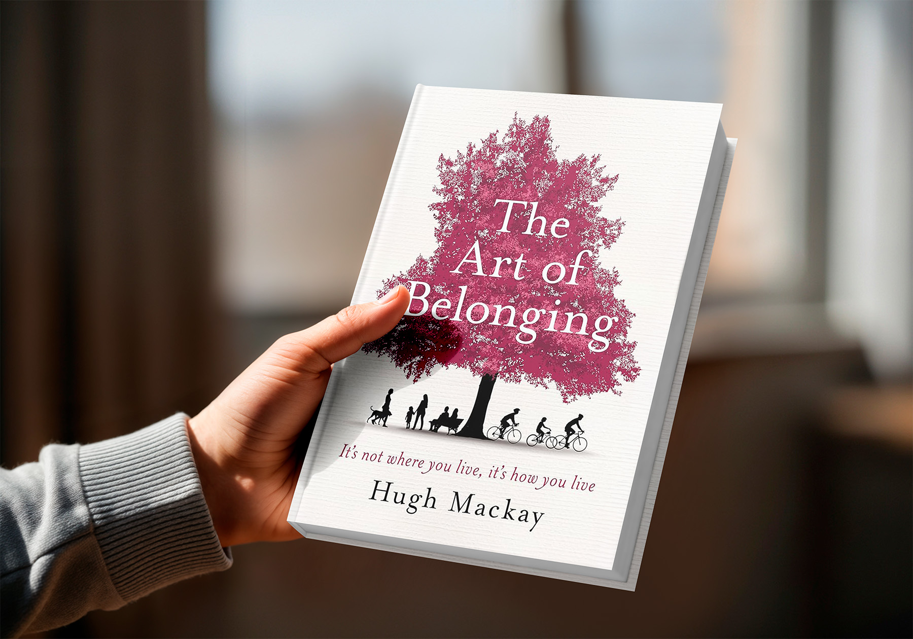 Hand holding a hard cover version of The Art of Belonging