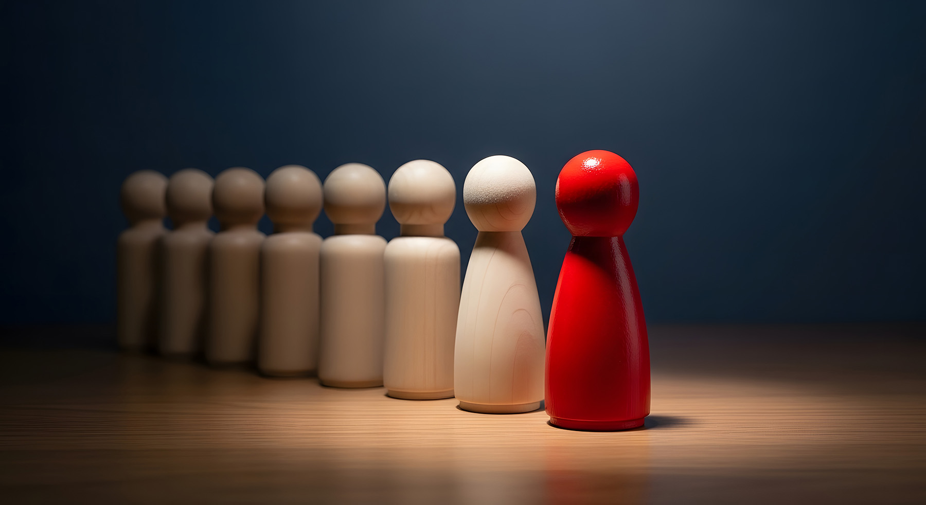A red simplifed carving of a person leads a line of unpainted figures.