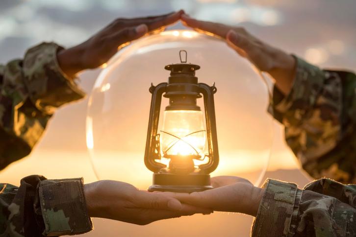 Many hands holding a lantern
