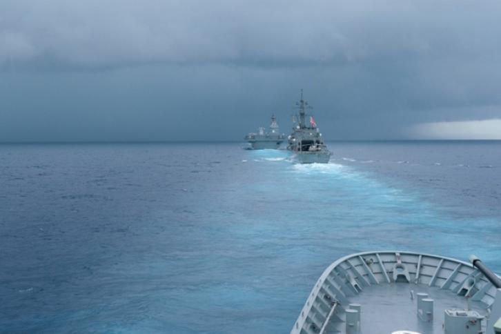 Modern Military Ships at sea headed towards a storm on the horizon.