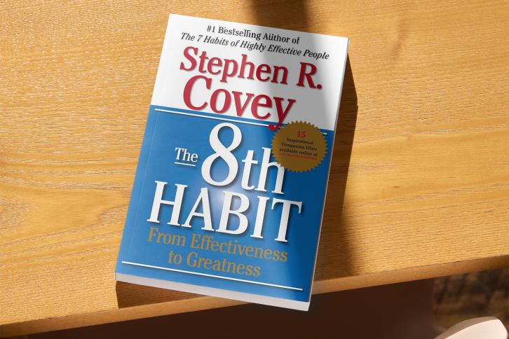 The 8th Habit book cover, the book is lying on a table 