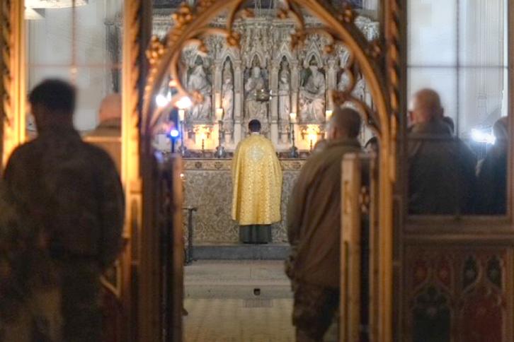 Evening Prayer, A priest stand facing the alter with uniformed soldiers in the congregation