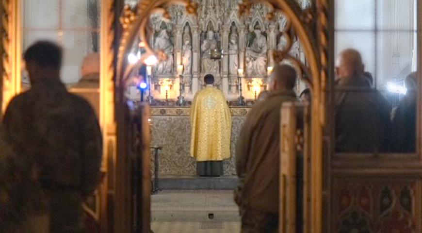 Evening Prayer, A priest stand facing the alter with uniformed soldiers in the congregation