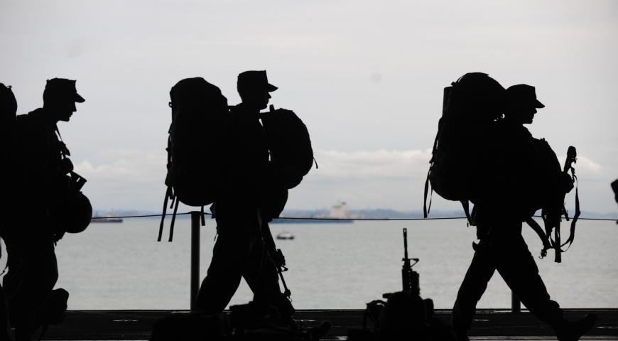 Military personnel walking in single file, silhouette 