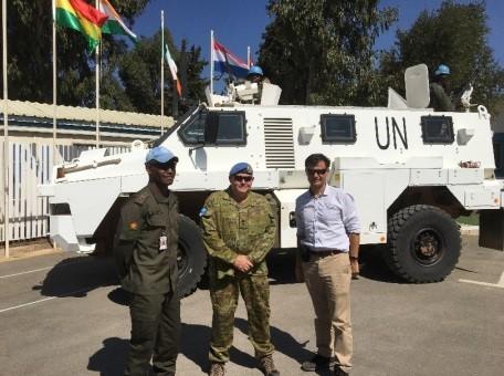 Lieutenant Colonel Leigh Scott Crawford with two men in front of U.N. truck.