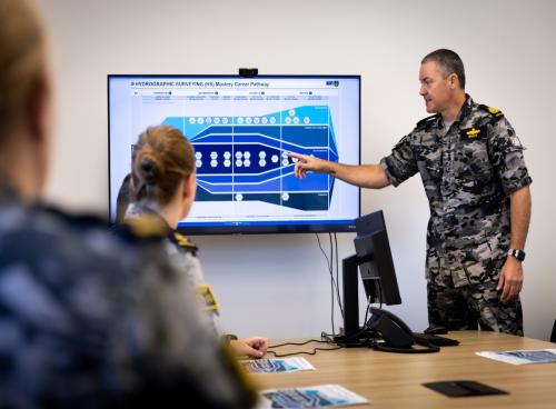 Educational session with navy presenting information on a screen.