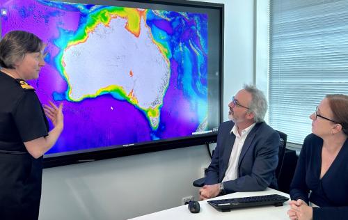 Three people looking at a large screen showing a coloured coded view of Australian waters