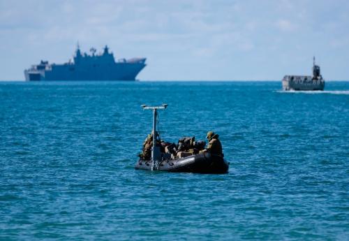 Inflatable outboard motor boat in the foreground with RAN ships in the background