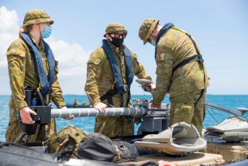Three Royal Australian Navy sailors preparing their geospatial survey equipment